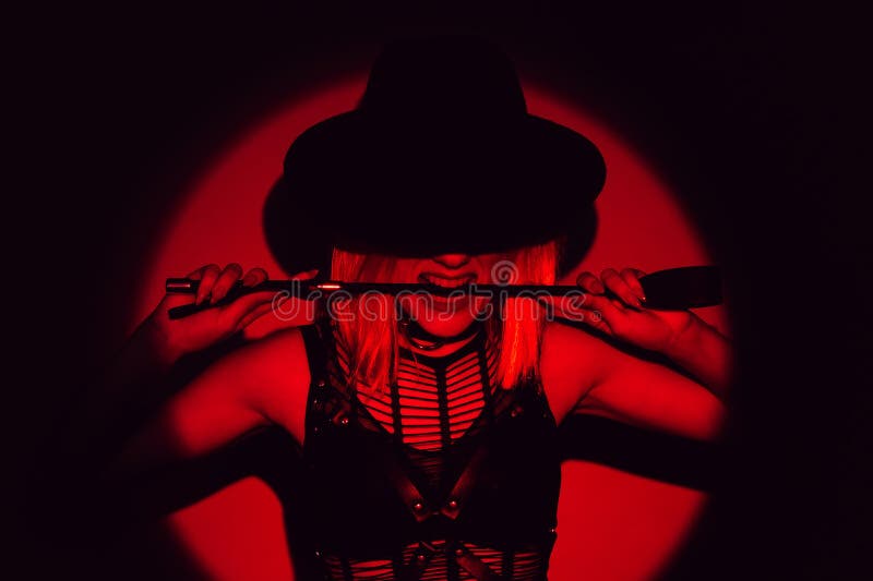 sexy girl in underwear and hat holds flogger whip in teeth. BDSM concept of a dominant woman