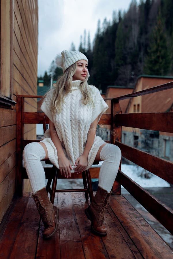 A Girl in a White Sweater and Stockings on the Balcony Admires the ...
