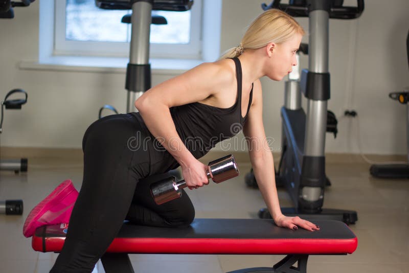Sexy jong atletiekmeisje die de oefeningen van de domorenpers doen Fitness gespierde vrouw in de zwarte training van de sportkled stock afbeeldingen Sexy jong atletiekmeisje die de oefeningen van de domorenpers doen Fitness gespierde vrouw in de zwarte training van de sportkled stock afbeeldingen
