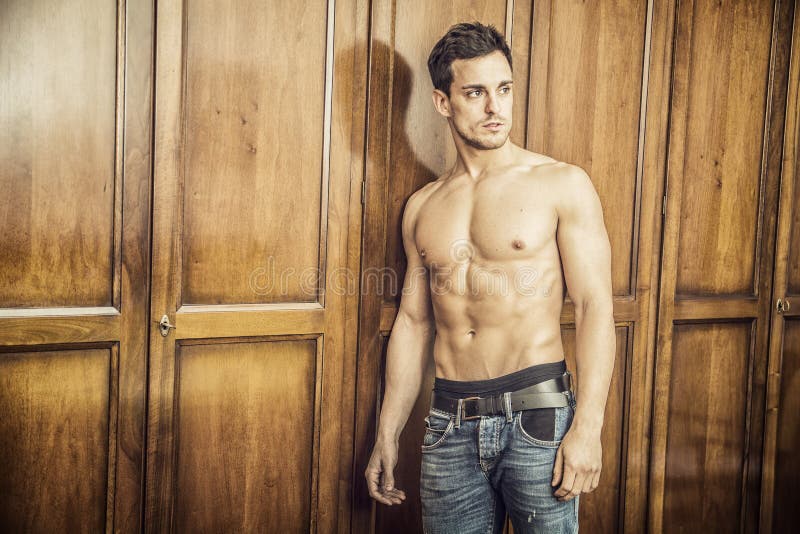 Sexy knappe jonge mens die zich shirtless tegen garderobe bevinden royalty-vrije stock foto Sexy knappe jonge mens die zich shirtless tegen garderobe bevinden royalty-vrije stock foto