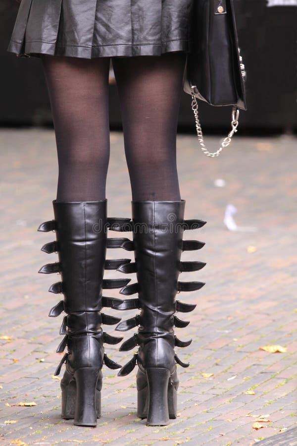 Model wearing black leather boots, miniskirt, pantyhose and purse in the street. Street style fashion. Model wearing black leather boots, miniskirt, pantyhose and purse in the street. Street style fashion.