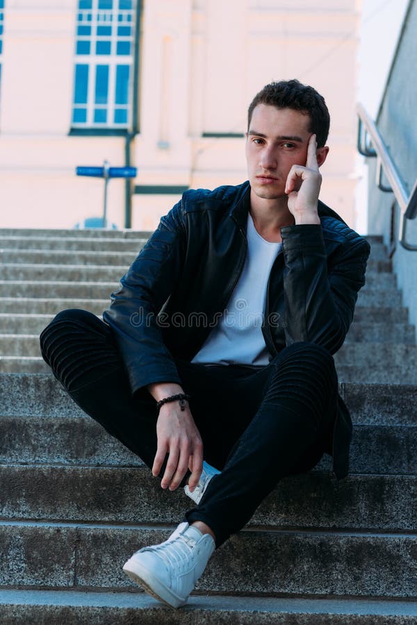 Man Posing Sits on the Steps Near Railing. Handsome Young Man in ...