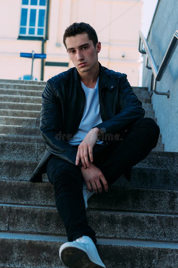 Man Posing Sits on the Steps Near Railing. Handsome Young Man in ...