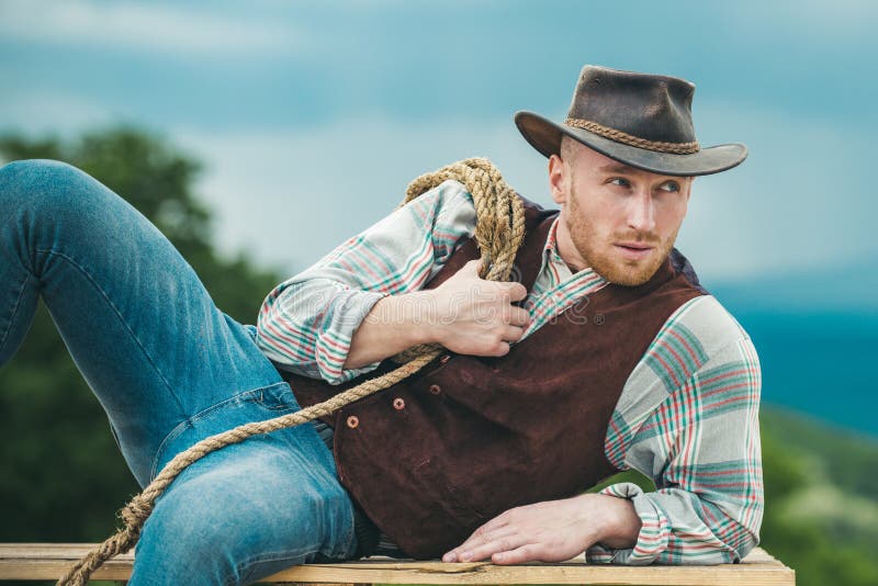 Sexy masculine stylish cowboymacho man som håller lasso-rep Mönster i västlig stil Handsome cowboyen i plaid-skjortan på royaltyfri fotografi