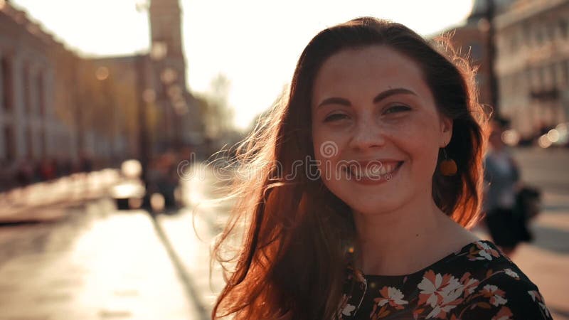 Sexy Mädchen mit dem langen roten Haar, das sich herum dreht und auf der Kamera im Freien lächelt stock video footage Sexy Mädchen mit dem langen roten Haar, das sich herum dreht und auf der Kamera im Freien lächelt stock video footage