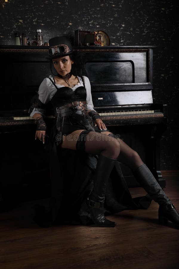 Sexy nettes steampunk Mädchen, das nahe bei dem Klavier sitzt stockfotografie Sexy nettes steampunk Mädchen, das nahe bei dem Klavier sitzt stockfotografie