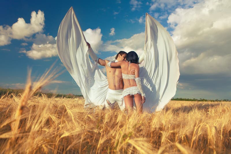Lovers with white wings on wheat field