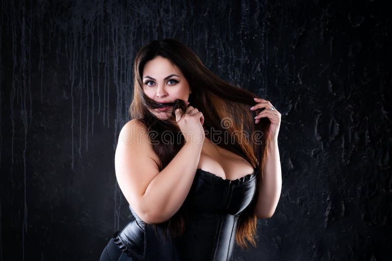 Sexy woman in corset squeezing breast by hands Stock Photo by