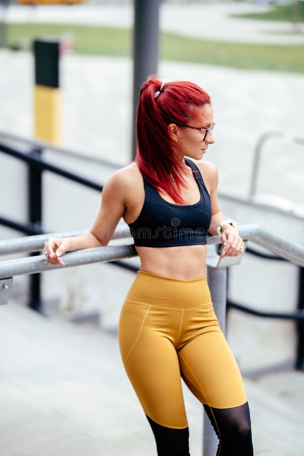 Cute redhead woman wearing green sports bra and blue yoga pants