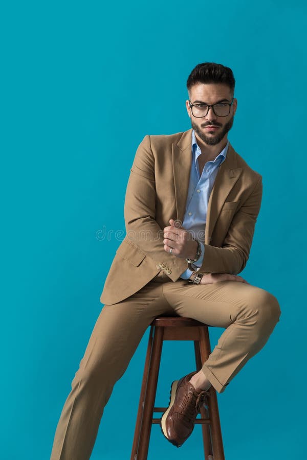 Sexy unshaved businessman with glasses holding arms in fashion pose