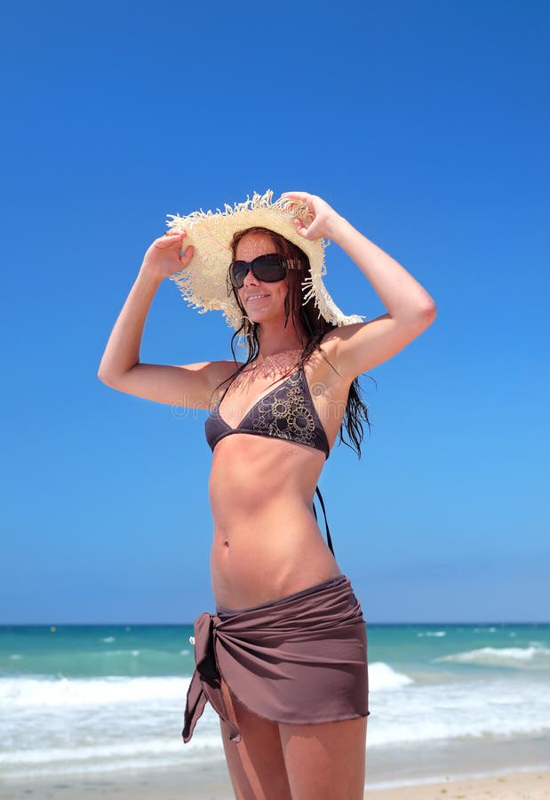 Sexy mladé ženy v bikinách úprava klobúk na slnečnej pláži na dovolenke.