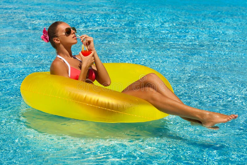 woman in bikini enjoying summer sun and tanning during holidays in pool with a cocktail