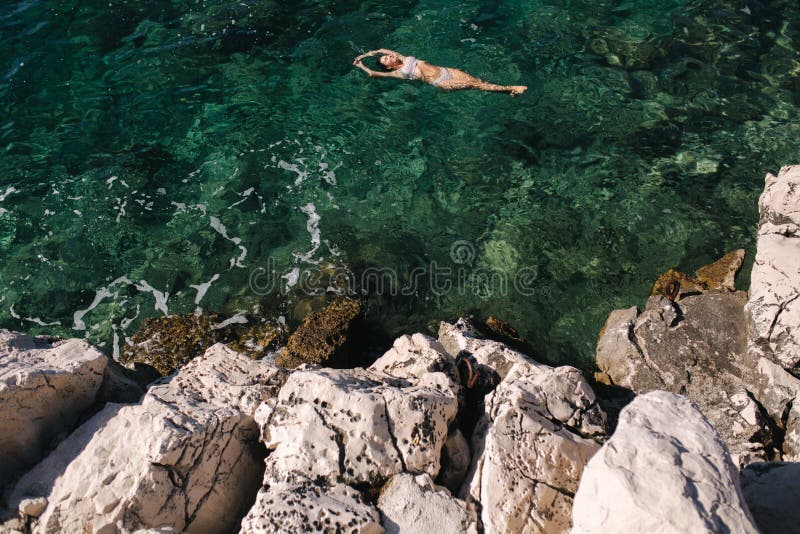 Sexy woman in bikini lying on the water. Attractive young woman enjoying summer sun. Beautiful lagoon. Woman swin in the