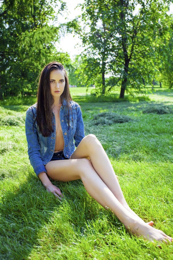 woman in blue jeans jacket on green grass in summer park