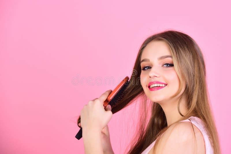 woman comb long straight hair. Girl with hair brush on pink background. Fashion model brush her beautiful hair