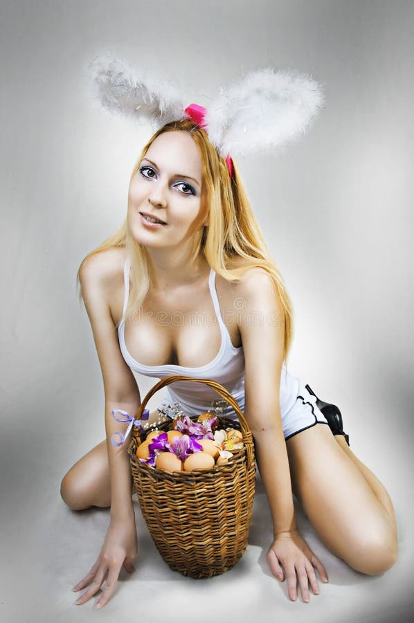 Young blondie woman easter bunny with big breast on gray background with ba...