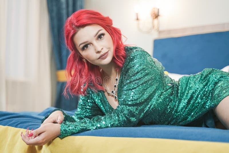 Sexy woman in green stylish sparkling glitter dress ready for christmas party and relaz by waiting in her bed alone stock photos Sexy woman in green stylish sparkling glitter dress ready for christmas party and relaz by waiting in her bed alone stock photos