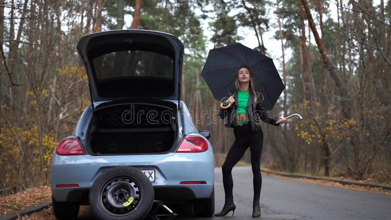Sexy woman on the heels with broken car on the empty road waiting for help. Concept of sexuality and fetish