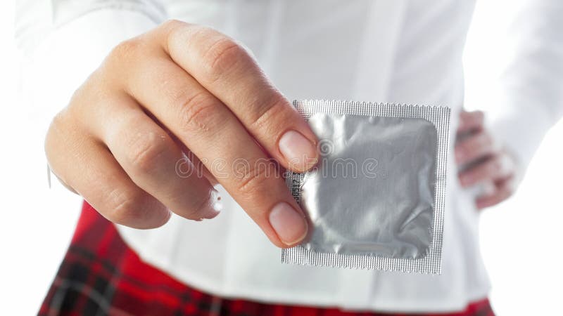 Sexy woman in school uniform holding condom in hand. Concept of contraception and safe sex..