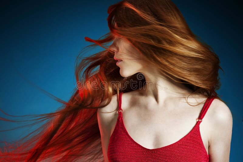 La giovane e Sexy capelli rossi donna in abito rosso su sfondo blu scuro.