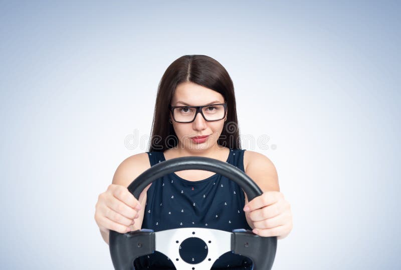 Sexy young smiling happy girl with glasses driving a car, front view