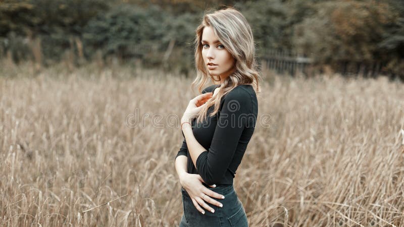 young woman in a black shirt standing in a corn field.