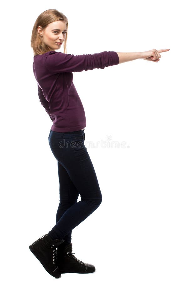 Young woman standing sideways pointing forwards with her arm towards the ri...