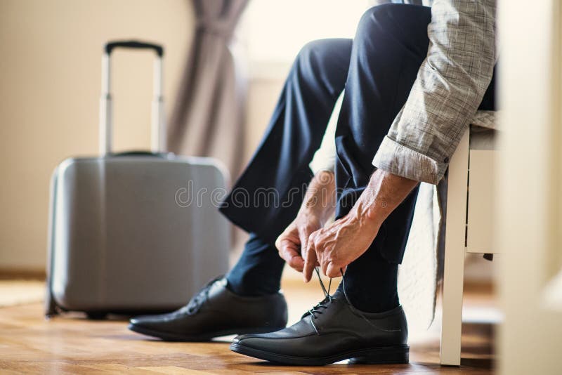 Seção mestra do homem de negócios em uma viagem de negócios que senta-se em uma sala de hotel, amarrando laços fotos de stock royalty free Seção mestra do homem de negócios em uma viagem de negócios que senta-se em uma sala de hotel, amarrando laços fotos de stock royalty free