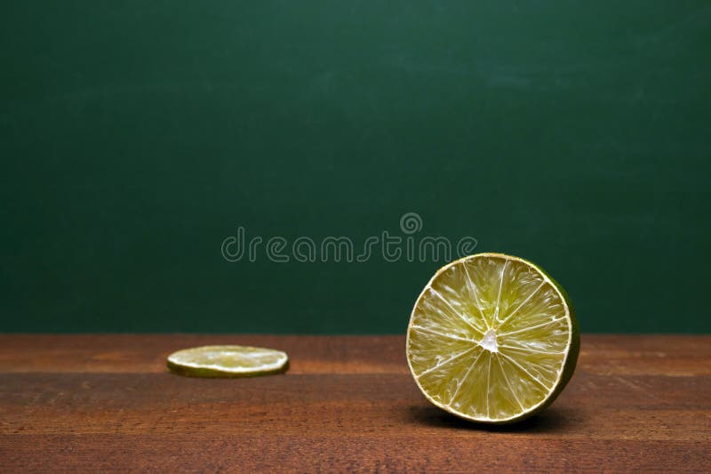 Seção transversal de um cal e uma fatia do cal em uma tabela de madeira Fundo verde Acento orgânico aos sabores dos alimentos e d imagens de stock royalty free Seção transversal de um cal e uma fatia do cal em uma tabela de madeira Fundo verde Acento orgânico aos sabores dos alimentos e d imagens de stock royalty free