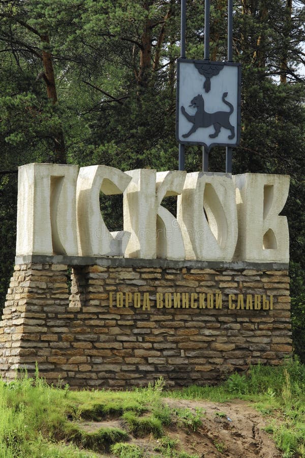 Pskov, Russia - July 20, 2014: Road sign at the entrance to the city of Pskov with the inscription in Russian `Pskov` and `City of military Glory` with the coat of arms of the city with the image of a leopard. Pskov, Russia - July 20, 2014: Road sign at the entrance to the city of Pskov with the inscription in Russian `Pskov` and `City of military Glory` with the coat of arms of the city with the image of a leopard