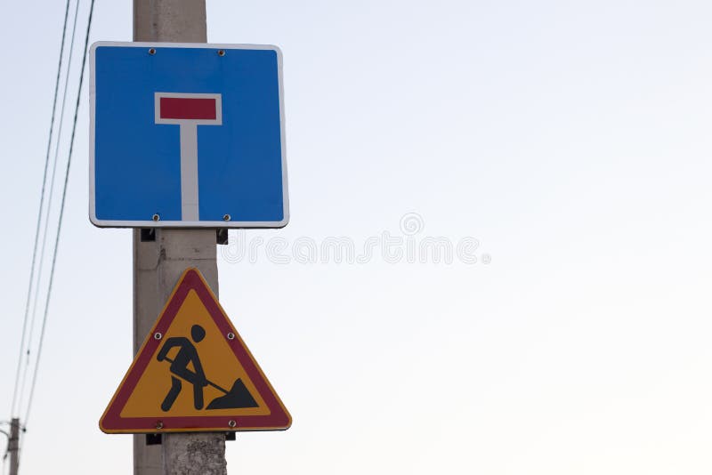 Señal de peligro triangular amarilla brillante; Atención, trabajo a continuación, y calle sin salida en el escudo azul cuadrado e fotos de archivo libres de regalías Señal de peligro triangular amarilla brillante; Atención, trabajo a continuación, y calle sin salida en el escudo azul cuadrado e fotos de archivo libres de regalías