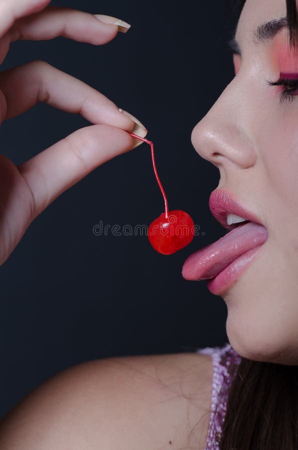 Señora bonita con los labios carnudos, mordiendo una cereza dulce fotos de archivo libres de regalías Señora bonita con los labios carnudos, mordiendo una cereza dulce fotos de archivo libres de regalías