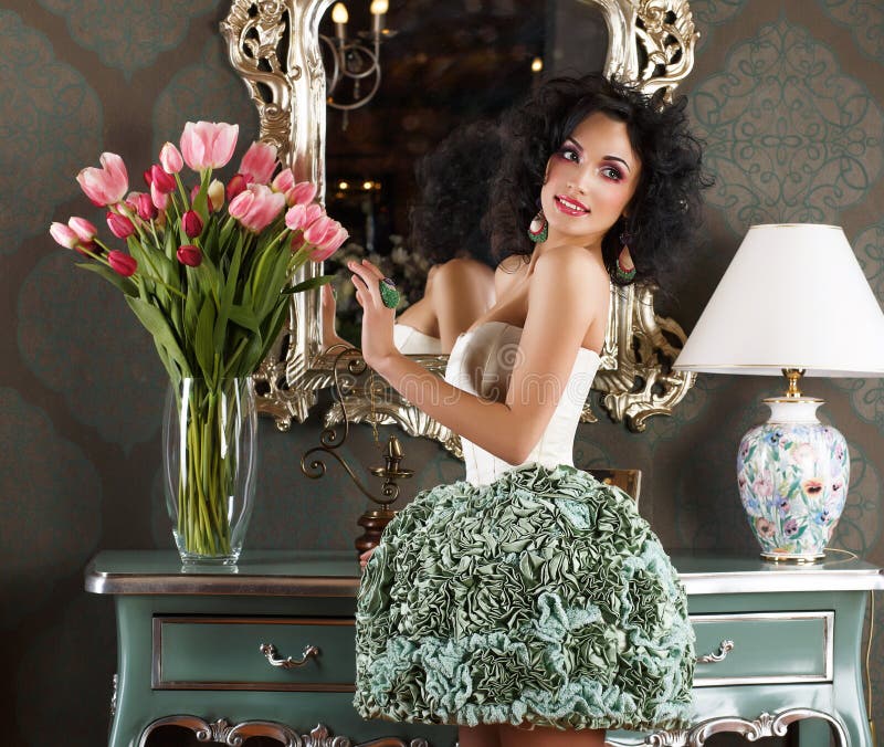 Mujer atractiva hermosa en interior retro con el florero de flores. Reflexión fotos de archivo Mujer atractiva hermosa en interior retro con el florero de flores. Reflexión fotos de archivo