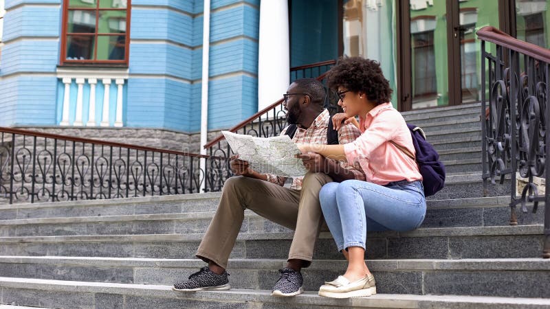Señora joven que señala en el mapa que busca la dirección con el novio, el viajar de los pares fotos de archivo Señora joven que señala en el mapa que busca la dirección con el novio, el viajar de los pares fotos de archivo