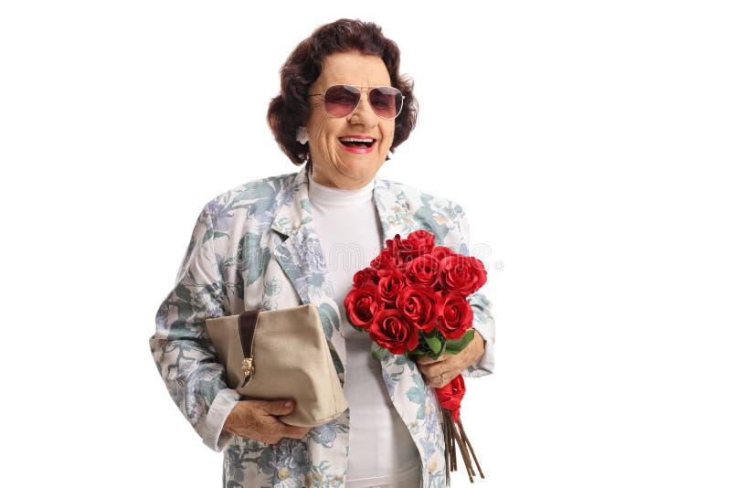 Señora mayor alegre con un monedero y un manojo de rosas rojas que sonríen en la cámara foto de archivo Señora mayor alegre con un monedero y un manojo de rosas rojas que sonríen en la cámara foto de archivo