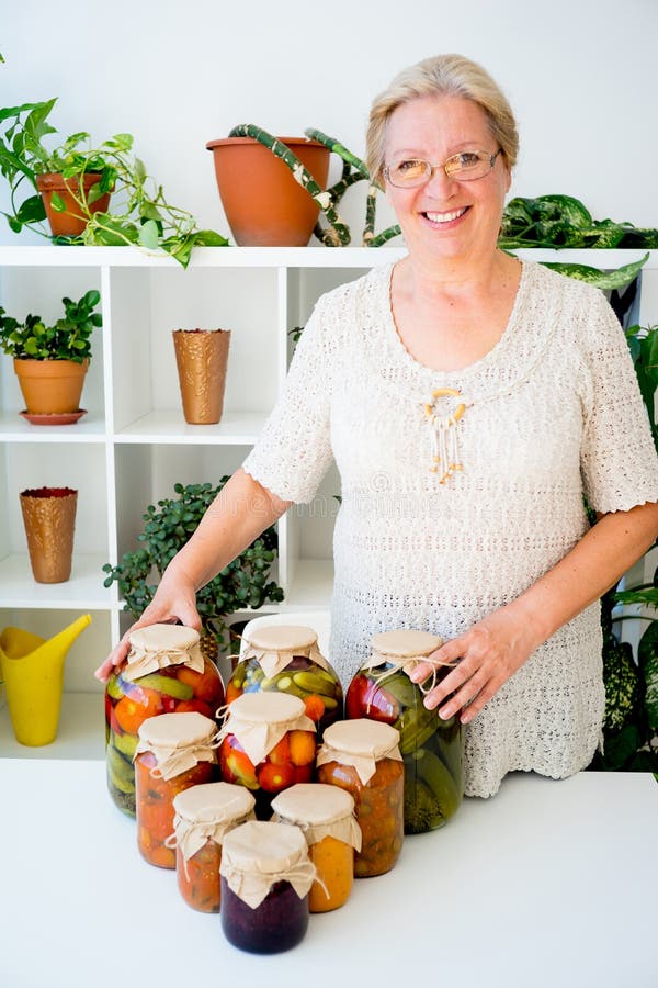 Señora mayor con la comida conservada en vinagre imagenes de archivo