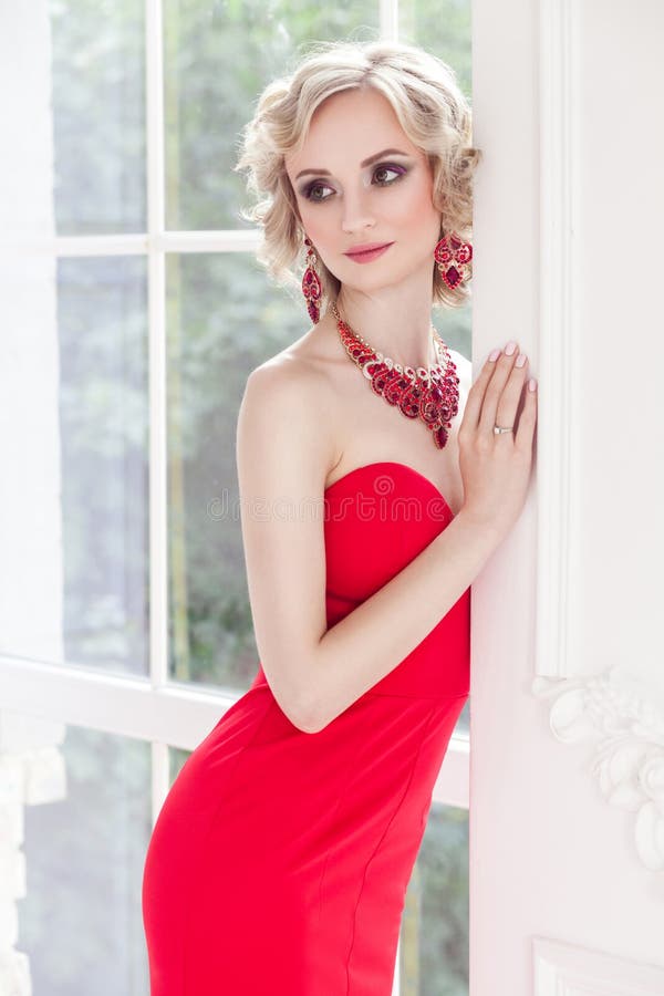 Señora sensual en actitud roja del vestido en estudio cerca de la ventana y de w blanco fotografía de archivo libre de regalías Señora sensual en actitud roja del vestido en estudio cerca de la ventana y de w blanco fotografía de archivo libre de regalías