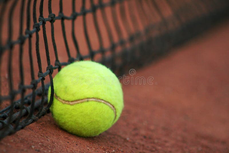 Tennis ball on a red court with the tennis net. Tennis ball on a red court with the tennis net