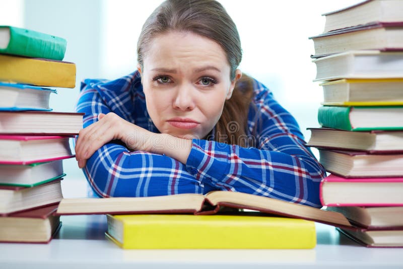 Portrait of a frustrated student being surrounded with piles of books. Portrait of a frustrated student being surrounded with piles of books