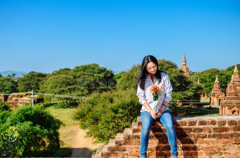 Sguardi della ragazza ai rosees che si siedono sulla pagoda a Bagan, Myanmar immagini stock libere da diritti Sguardi della ragazza ai rosees che si siedono sulla pagoda a Bagan, Myanmar immagini stock libere da diritti