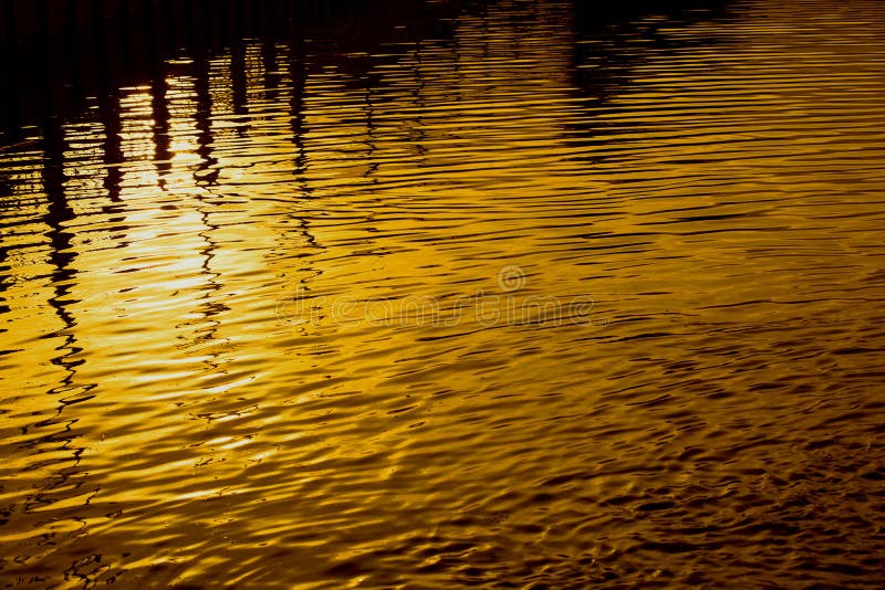 Shadows reflect the golden circle at dusk, the light from the sun reflects the water. A black silhouette