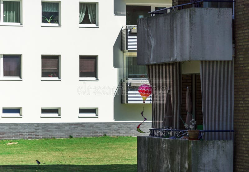 Shady dark settlement with terraced houses in a suburb, with a bright colorful toy balloon on an ugly dirty old balcony royalty free stock photos
