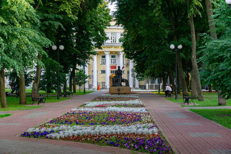 Shady street with beautiful flower bed and monument to Bunin stock photo Shady street with beautiful flower bed and monument to Bunin stock photo