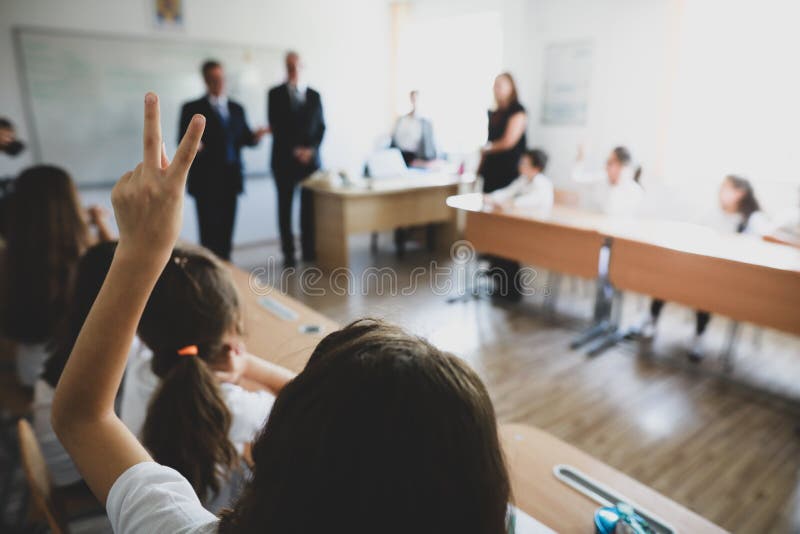 Shallow depth of field image with a pupil raised hand to answer or put a question or to volunteer for a task in the classroom