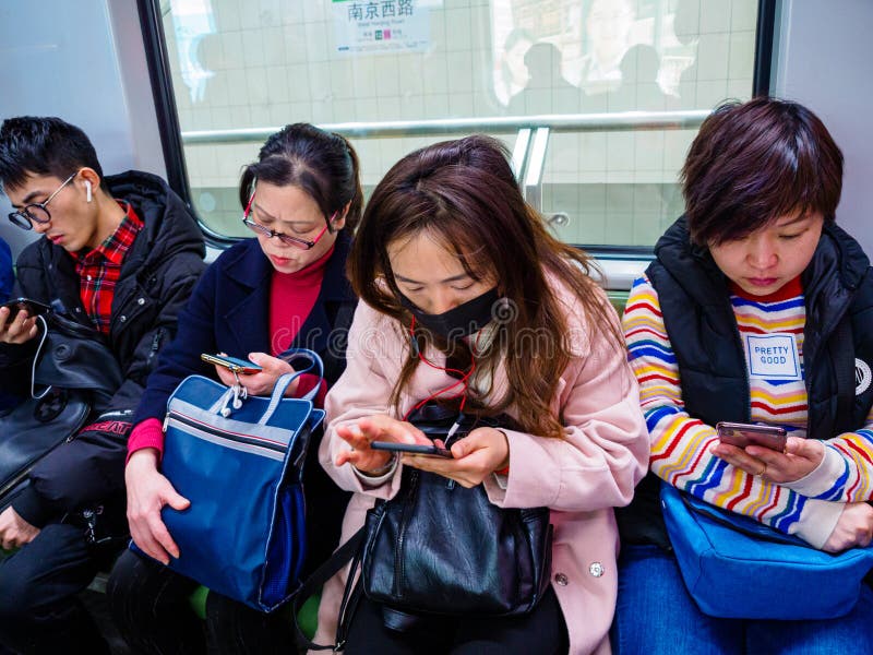 SHANGHAI, CHINA - 12 BRENG 2019 in de war - een rij van forenzen op Metro van Shanghai allen op hun smartphones China heeft uiter stock afbeeldingen SHANGHAI, CHINA - 12 BRENG 2019 in de war - een rij van forenzen op Metro van Shanghai allen op hun smartphones China heeft uiter stock afbeeldingen