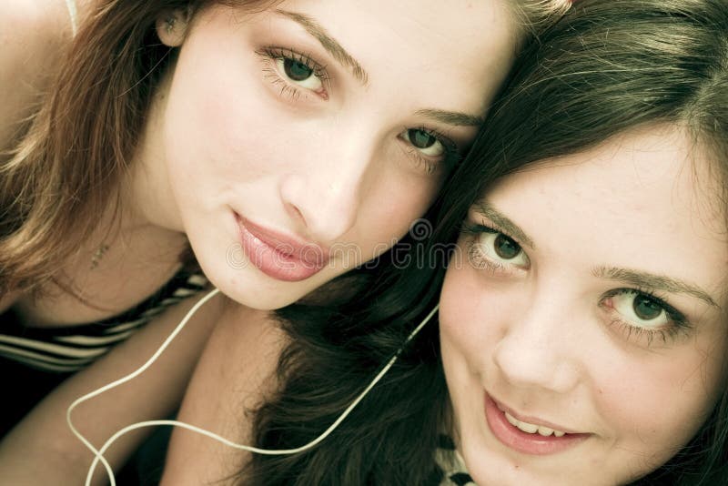 Young women listening to music and sharing earphones. Young women listening to music and sharing earphones.