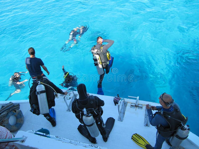 SHARM EL SHEIKH, EGYPTE - december 29, 2009: De duikers springen in de mooie turkooise oceaan van de kant van een wit jacht in stock foto SHARM EL SHEIKH, EGYPTE - december 29, 2009: De duikers springen in de mooie turkooise oceaan van de kant van een wit jacht in stock foto