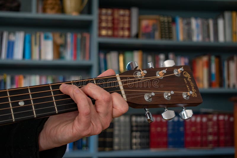 A Womans hand plays a C Chord on a classic Martin D28 guitar. Colorful image.