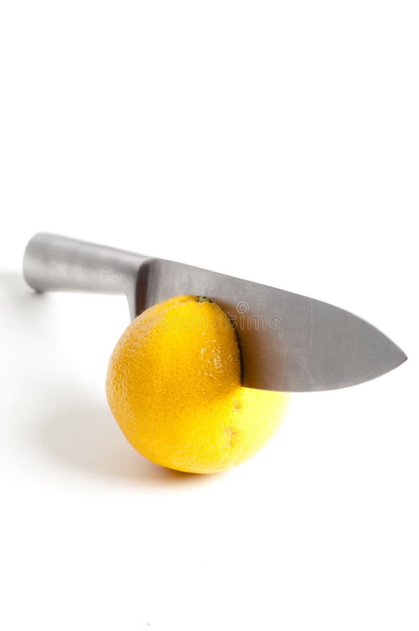 Sharp knife cutting into orange