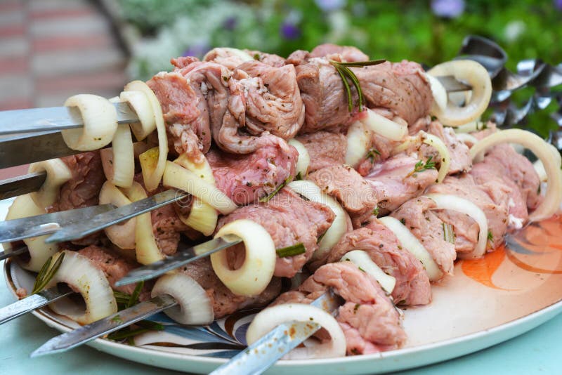 Grilling marinated shashlik preparing on a barbecue grill over charcoal.  Shashlik is a form of Shish kebab popular in Eastern Europe. Shashlyk (meaning  skewered meat) was originally made of lamb. Stock Photo